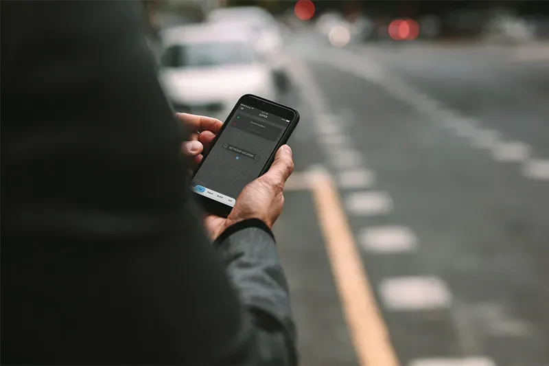 Close up of person holding phone and using rideshare app